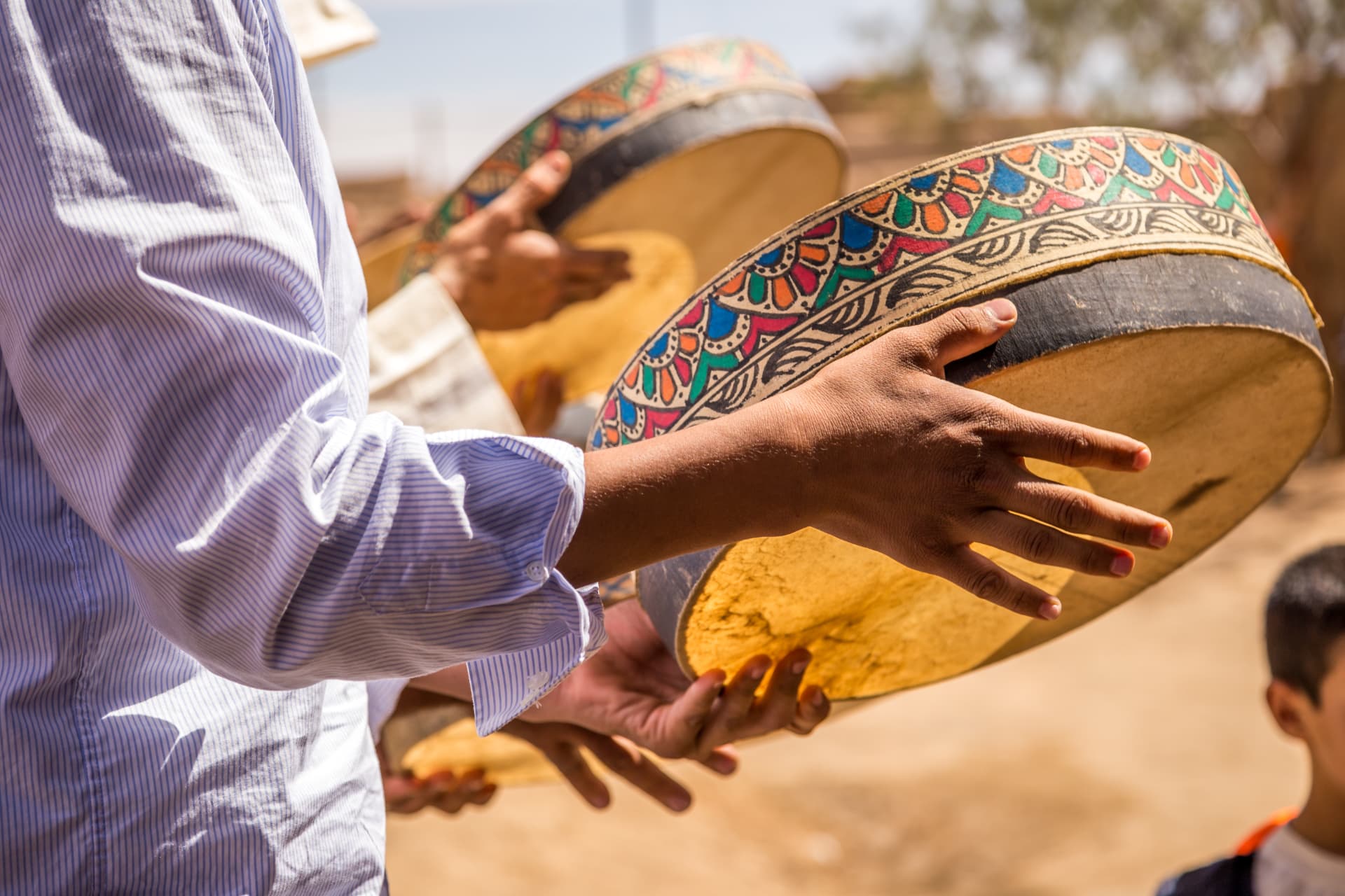 Hands playing decorated Moroccan frame drums