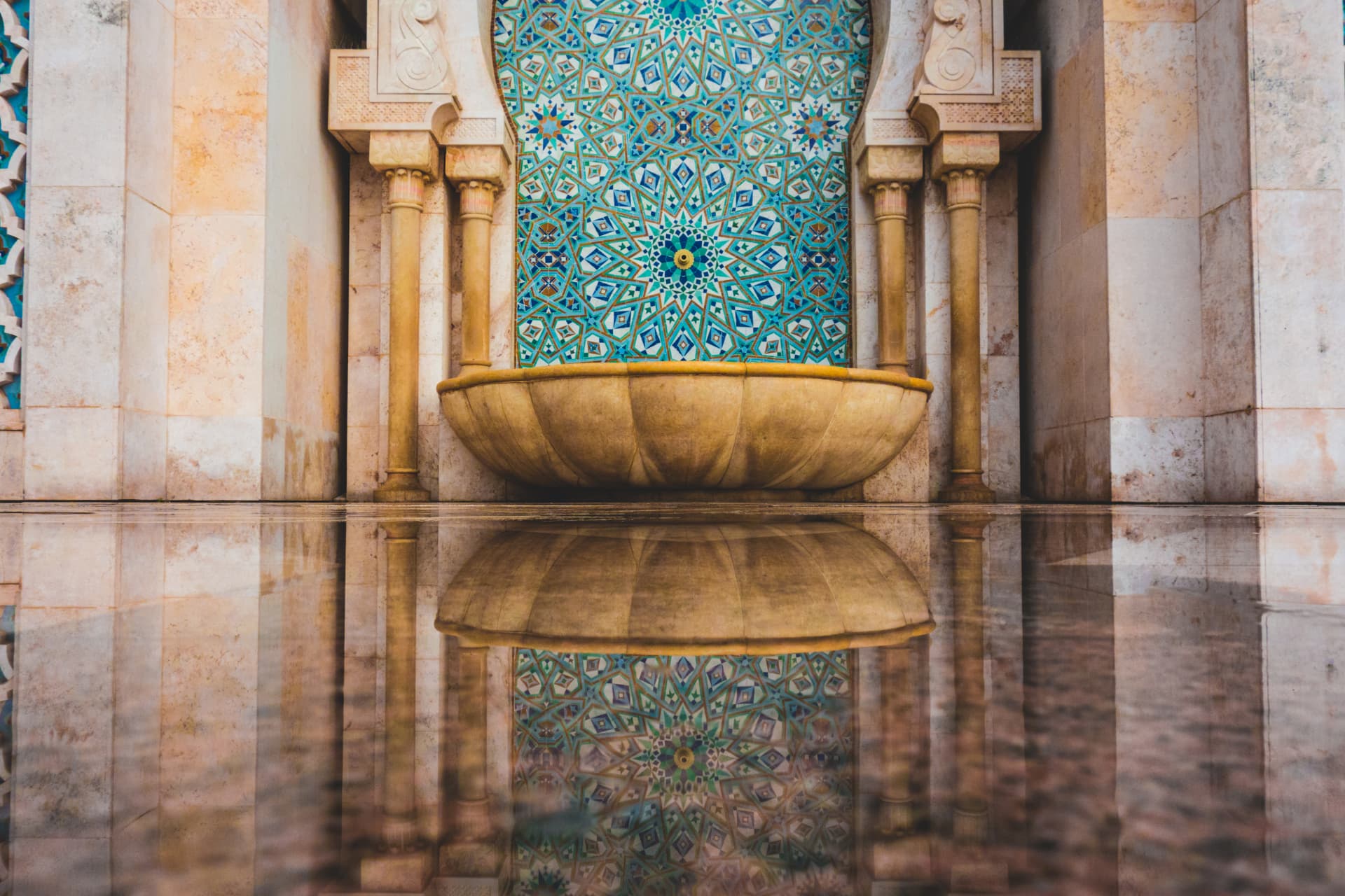 Intricate blue and gold zellige tilework and fountain in Fes